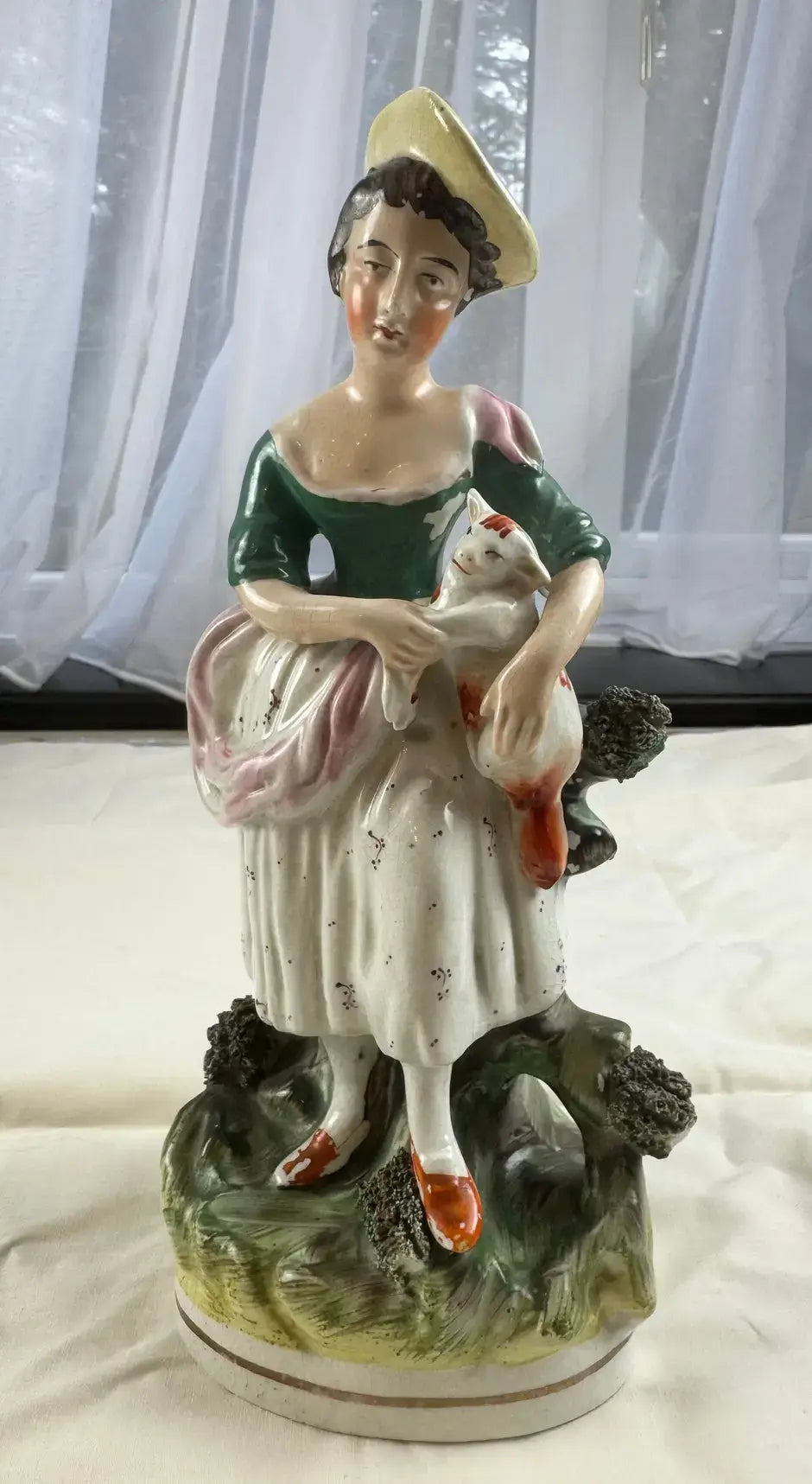 Exquisite 19th-century Staffordshire figurine of a woman holding a cat, showcasing Victorian elegance and charm.