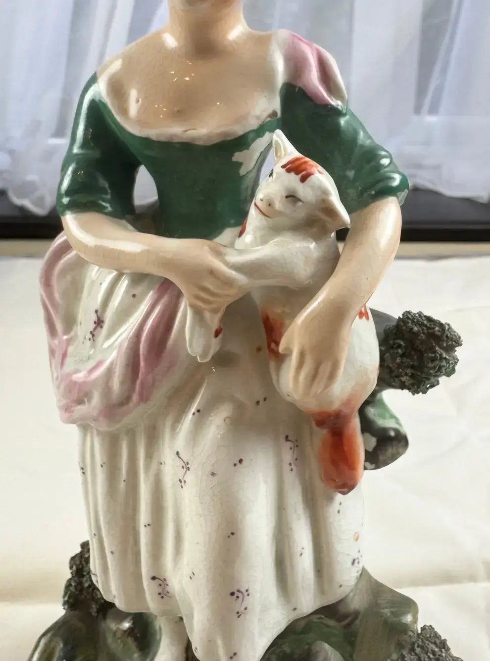 Exquisite 19th-century Staffordshire figurine of a woman with a cat, embodying Victorian elegance and charm.