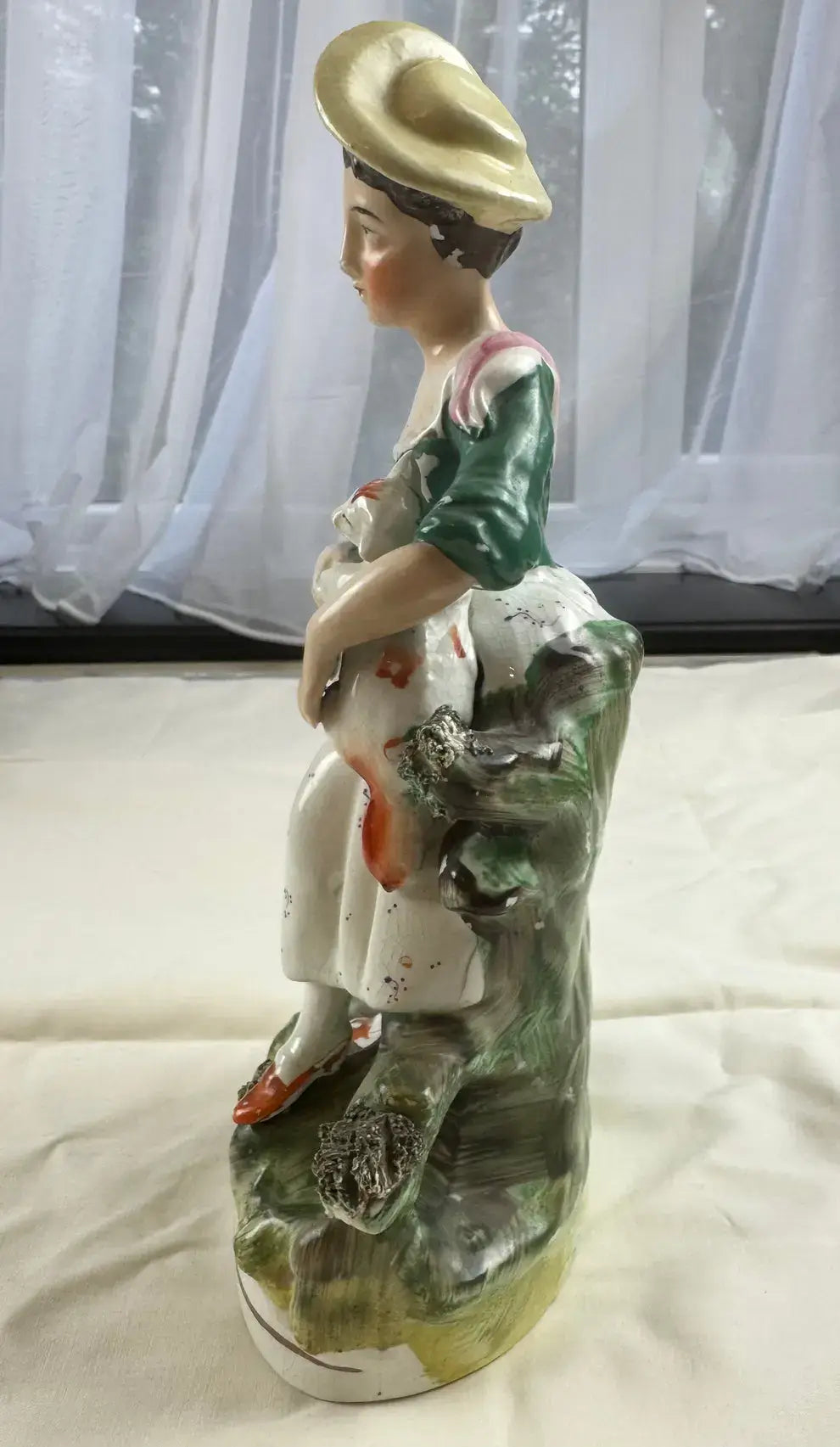 Exquisite 19th-century Staffordshire figurine of a woman in a yellow bonnet holding a cat, showcasing Victorian charm.
